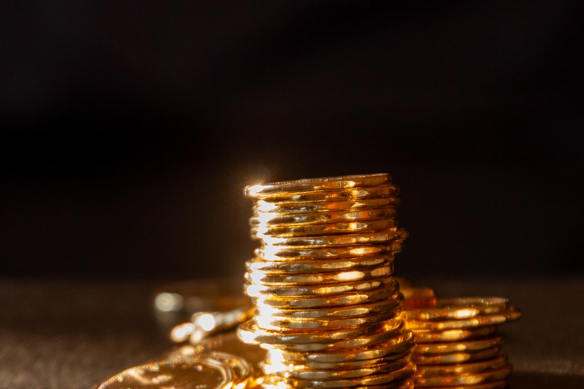 Gestapelte Goldmünzen auf dunklem Untergrund – Symbolbild für Sicherheit beim Goldkauf